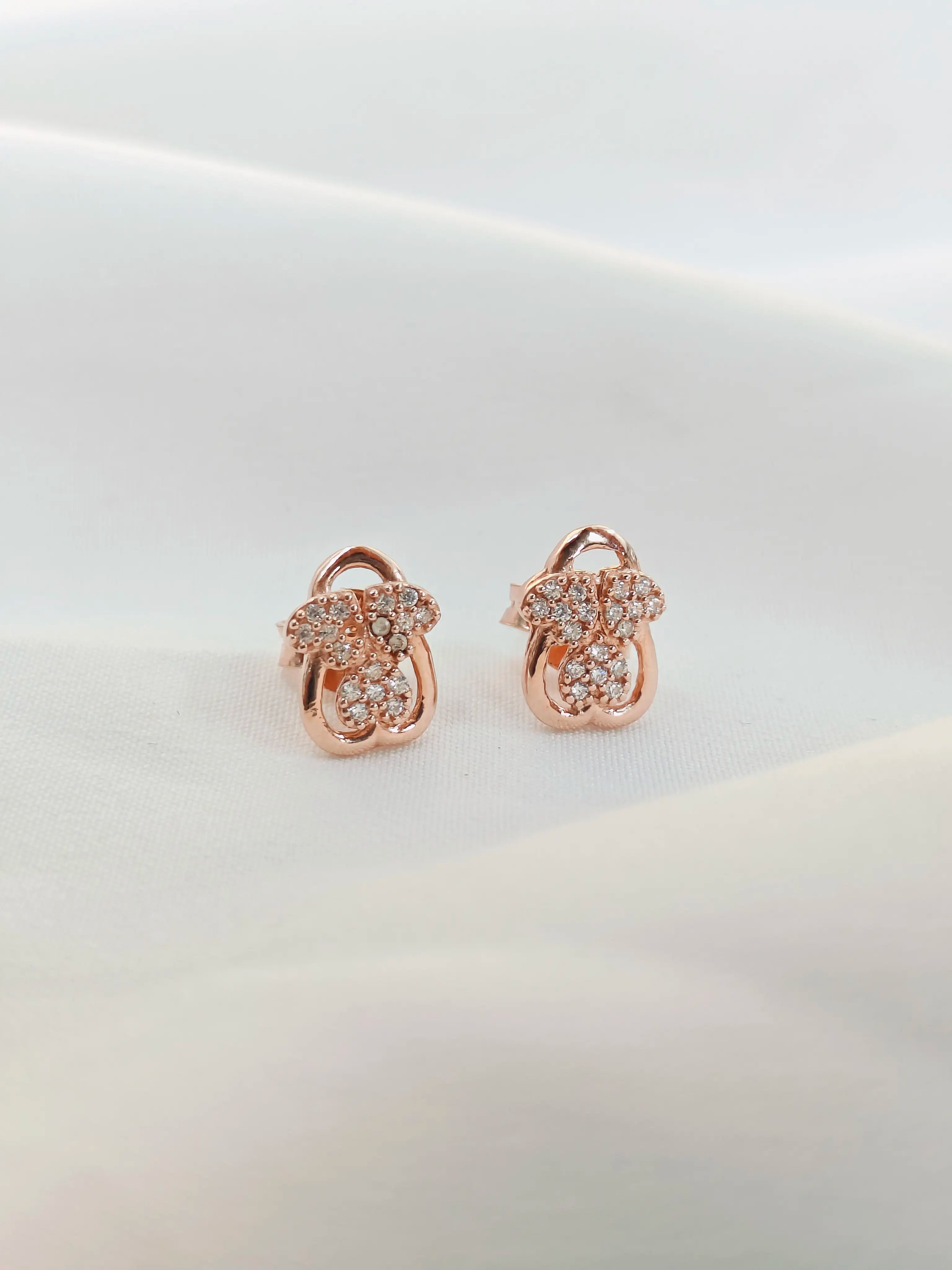 Rose gold earrings with diamond accents on a light background